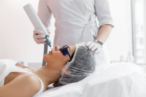 Caring about skin. Pretty nice woman wearing special eyewear while receiving facial skin treatment